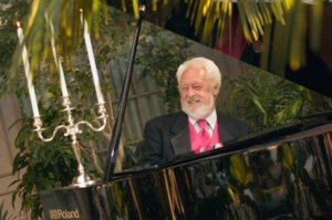 Bill Horn an Internationally known Concert artist sitting behind a piano with a candelabra siting on top